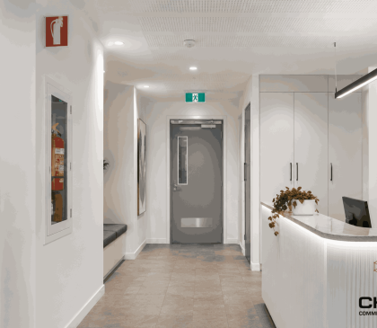 Commercial reception area in WA fitout with fire extinguisher cabinet, emergency exit signage and modern compliance-ready finishes.