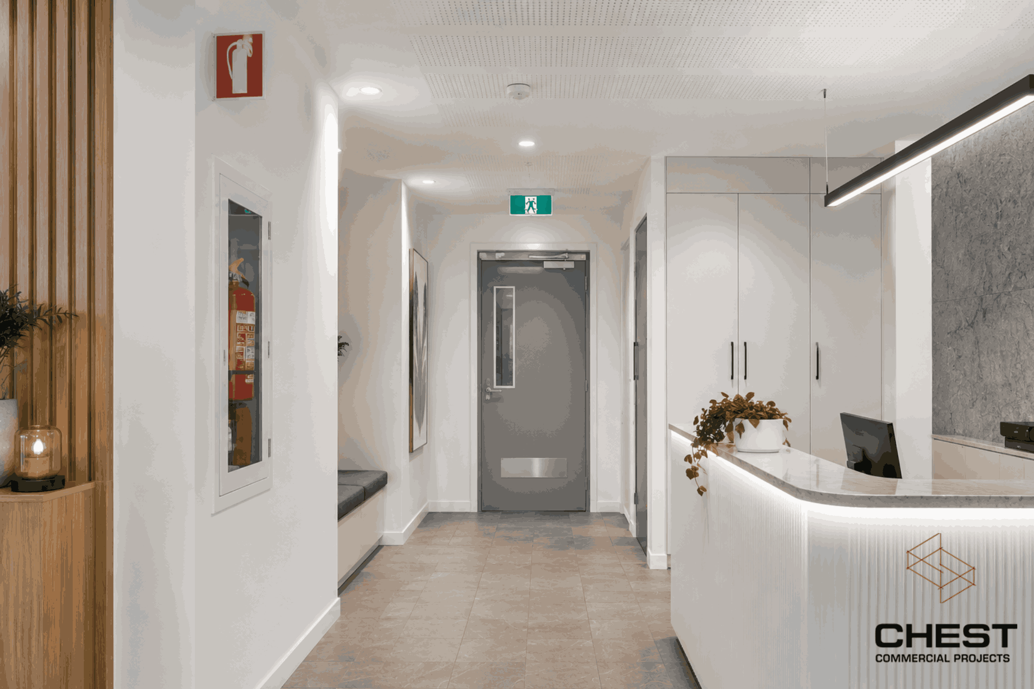 Commercial reception area in WA fitout with fire extinguisher cabinet, emergency exit signage and modern compliance-ready finishes.