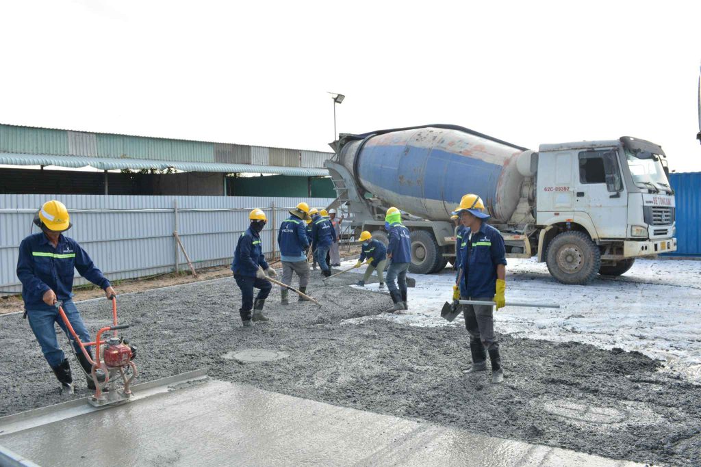 Construction workers pouring and levelling concrete at a parking lot