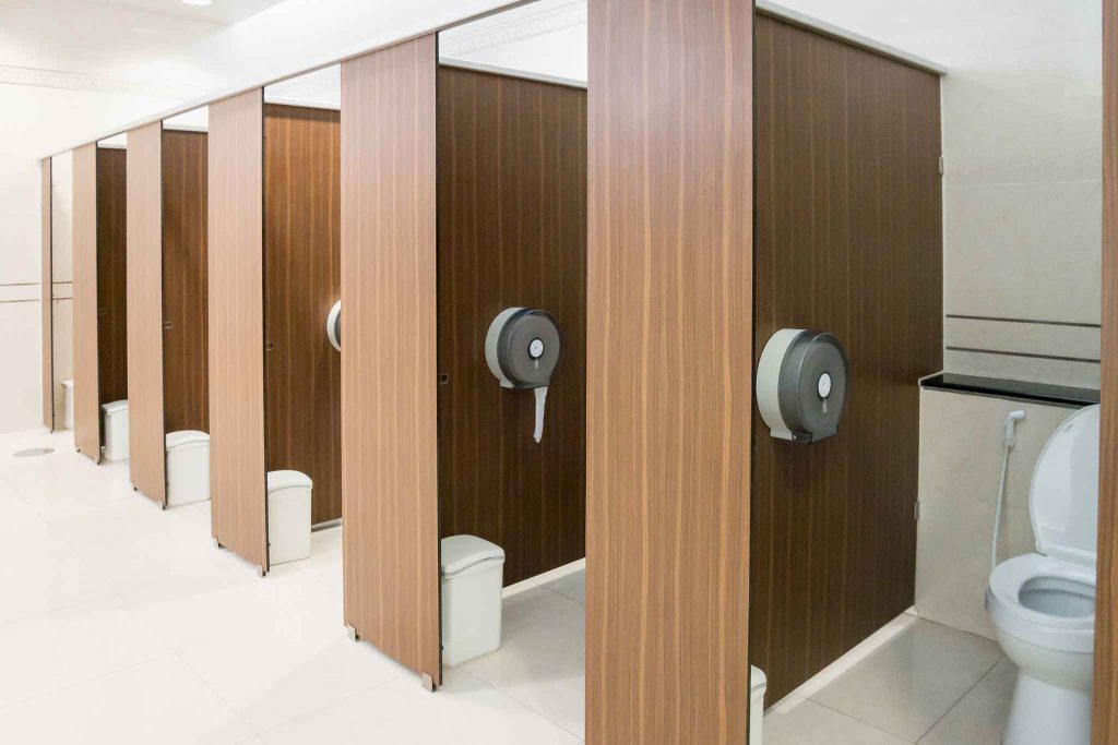**Alt text:**
Row of commercial toilet cubicles in a WA fitout, illustrating toilet occupancy and minimum facility requirements under NCC compliance
