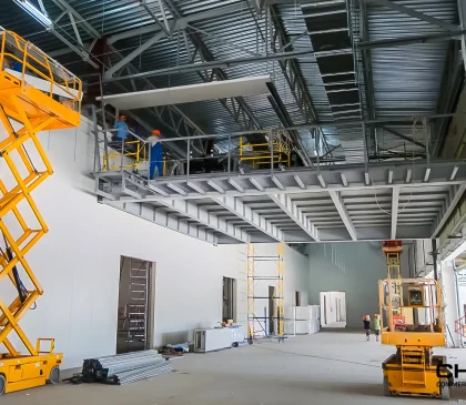 Workers using scissor lifts to construct a steel mezzanine inside a commercial warehouse fitout.